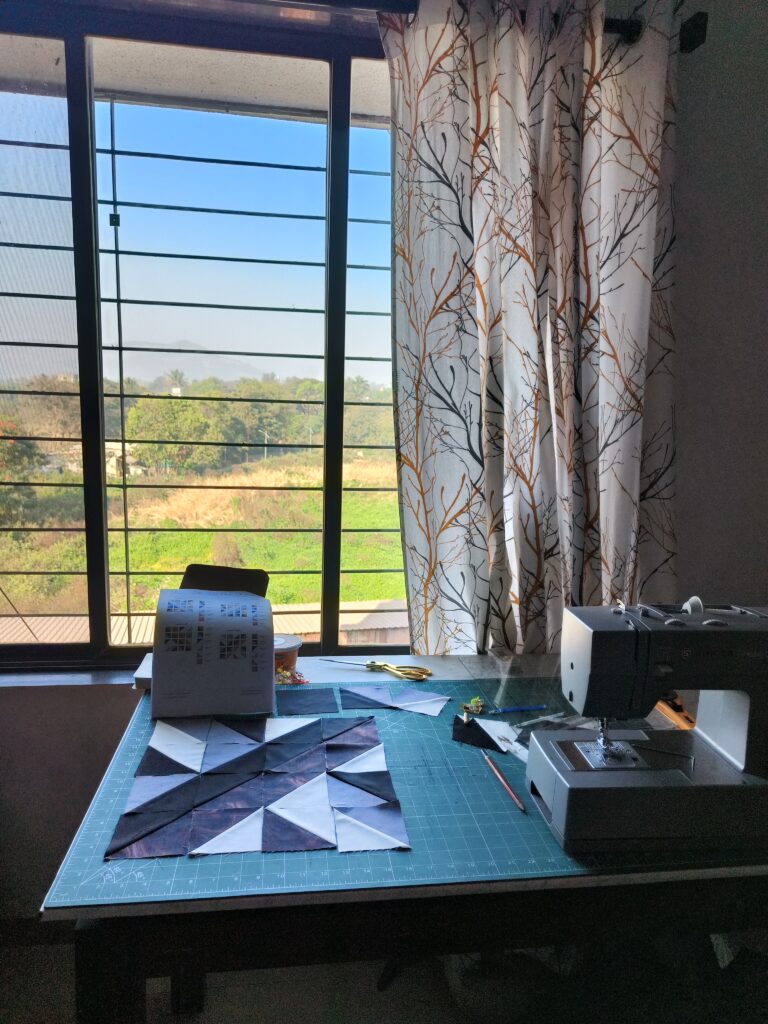 Ashmita sewing her first quilt at home, surrounded by fabric scraps and a Singer Heavy Duty machine.