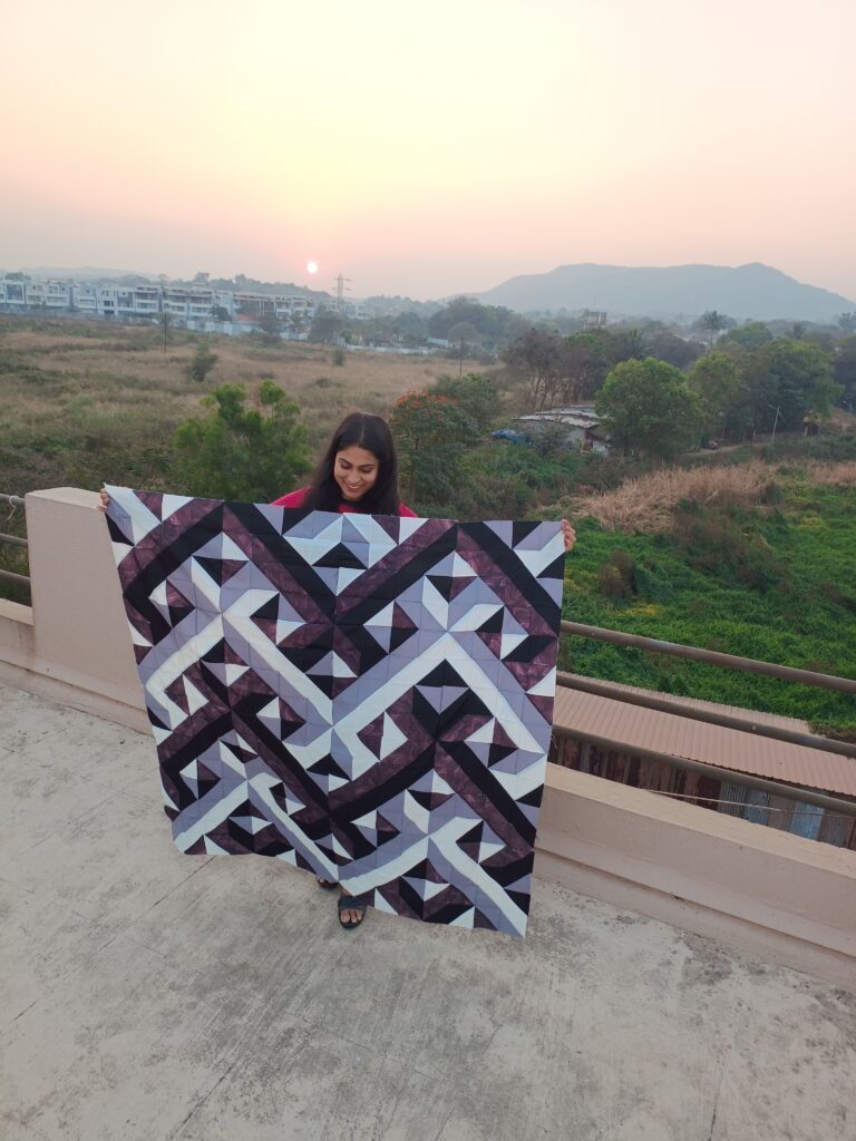 Symmetrical handmade quilt laid out flat, featuring modern and bold colors